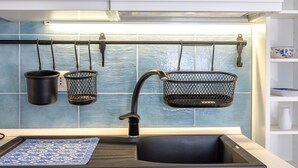 A kitchen with a black sink, a faucet, and two hanging pots. - Apartment 'Casa 20' with Private Terrace, Wi-Fi and Air Conditioning (Stintino)