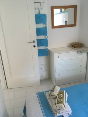 A bedroom with a bed, a dresser, a mirror, and a door with a towel rack.