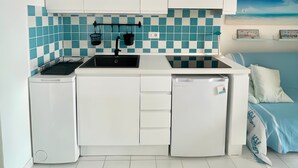 A compact kitchen with white cabinets, a tiled backsplash, a sink, and a dishwasher.