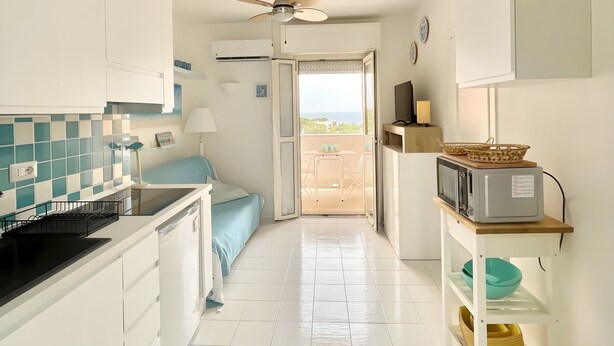 A kitchen with a microwave, a ceiling fan, and a view to the outside.