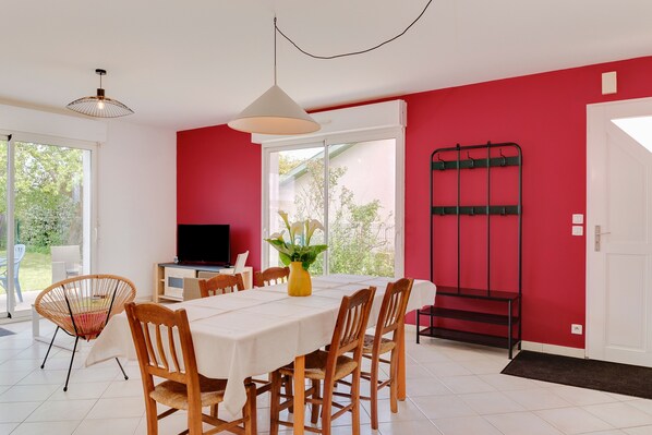 Un espace repas comprenant une table, des chaises, un téléviseur et une plante.