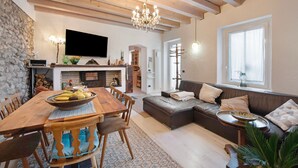A cozy living room with a wooden dining table, a sofa, and a television. - Holiday Home 'Haus Siloah Grole Di Desenzano' with Private Garden and Wi-Fi (GROLE di Desenzano)
