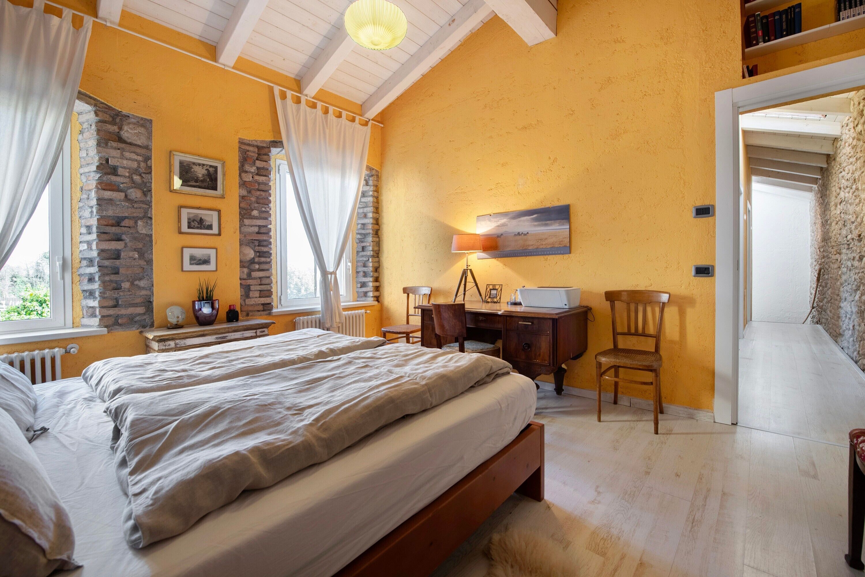 Une chambre à coucher avec un lit, un bureau, une chaise et une fenêtre avec des rideaux.