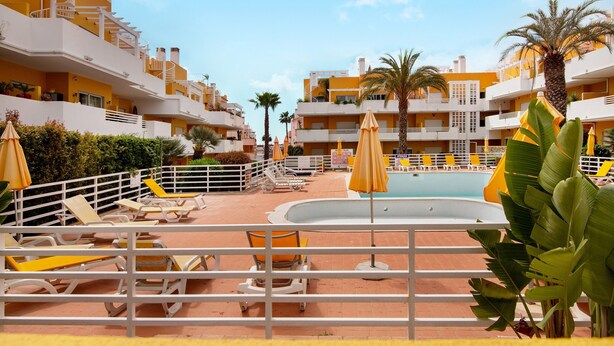 A resort with multiple balconies, a swimming pool, sun loungers, and palm trees. - Apartment 'Royal Cabanas Golf' with Shared Pool, Wi-Fi and Air Conditioning (Conceição de Tavira)