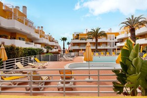 A resort with multiple balconies, a swimming pool, sun loungers, and palm trees. - Apartment 'Royal Cabanas Golf' with Shared Pool, Wi-Fi and Air Conditioning (Conceição de Tavira)