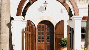 A white building with a wooden archway, a large wooden door, and a potted plant. - Hostal Boutique Canyamel - 102 Double room with Private Terrace, Wi-Fi, A/C and Sea View (Canyamel)