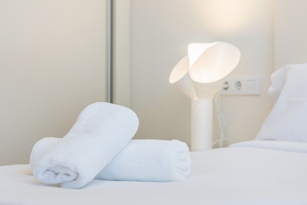 A neatly made bed with white linens, a white bedside lamp, and a wall socket. - Hostal Boutique Canyamel, 105 Double Rooms with Sea View, Private Terrace, Wi-Fi and a/c (Canyamel)