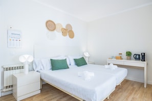 Habitación de hotel ordenada con cama, mesitas de noche, un escritorio y un tablón de anuncios en la pared.