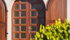 Une porte en bois avec un panneau de verre, flanquée de deux portails en arc, qui mène à un escalier en pierre.