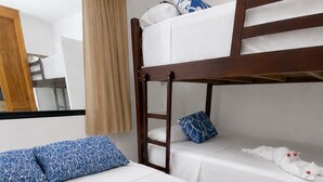 Une chambre d’hôtel avec un lit superposé, une couvre-lit blanche et un peignoir blanc orné de boutons dorés.