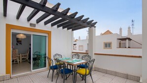 Un patio con mesa lista para comer, sillas y un área techada.