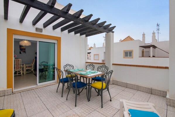A patio with a table set for dining, chairs, and a covered area.