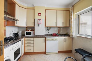 A compact kitchen with a stove, microwave, dishwasher, and cabinets.