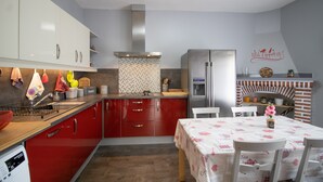 Une cuisine avec des meubles de rangement rouges, un réfrigérateur en acier inoxydable, un pare-feu en carrelage et un four à briques.