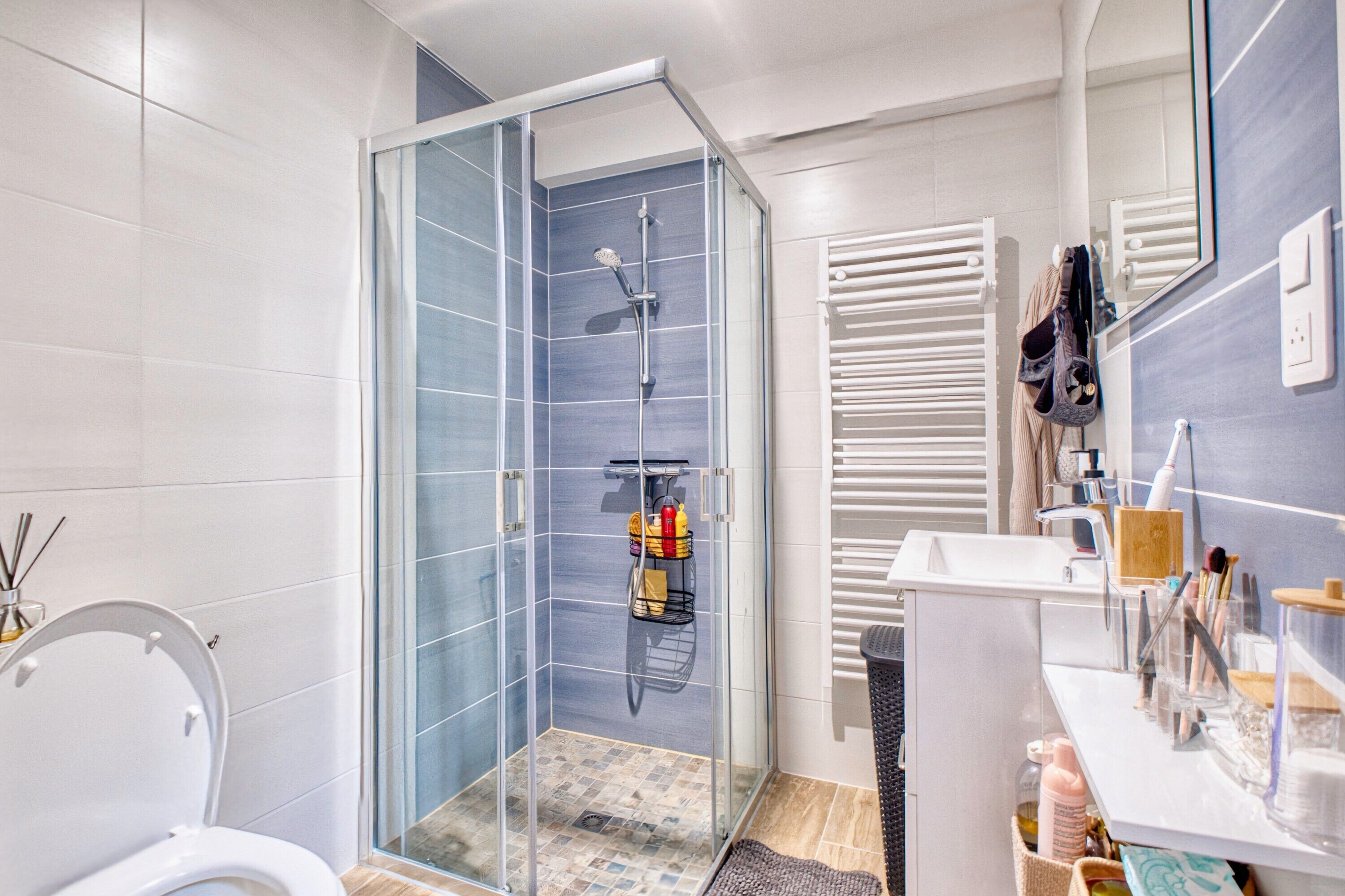 A modern bathroom with a glass-enclosed shower, a white toilet, a sink with a mirror, and a towel rack.