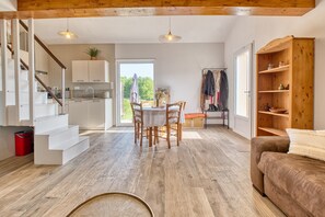 Ein geräumiger Wohnbereich mit einer Holztreppe, einem Esstisch mit Stühlen, einer Couch und einem Holzschrank.