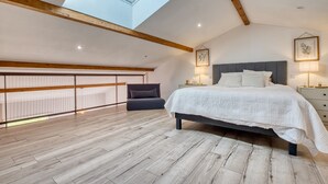 Ein Schlafzimmer mit Oberlicht, einem Bett, Nachttischlampen und Blick auf den Himmel.