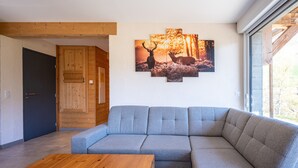 A modern living room with a sectional sofa, a wooden coffee table, and a wall-mounted deer painting.