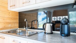 A modern kitchen with a stainless steel sink, a kettle, and a coffee maker.