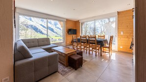A modern living room with a sofa, dining table, chairs, and a TV.