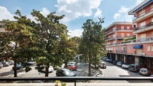 Vista de una calle con coches estacionados, árboles y edificios de varios pisos.