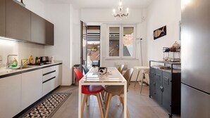 Una cocina moderna con comedor, un refrigerador y una escalera que sube a un nivel superior.