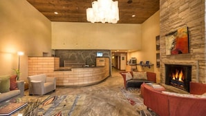 A lobby with a reception desk, a fireplace, and seating areas.