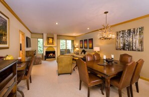 A dining area with a fireplace, a chandelier, and a large painting on the wall.