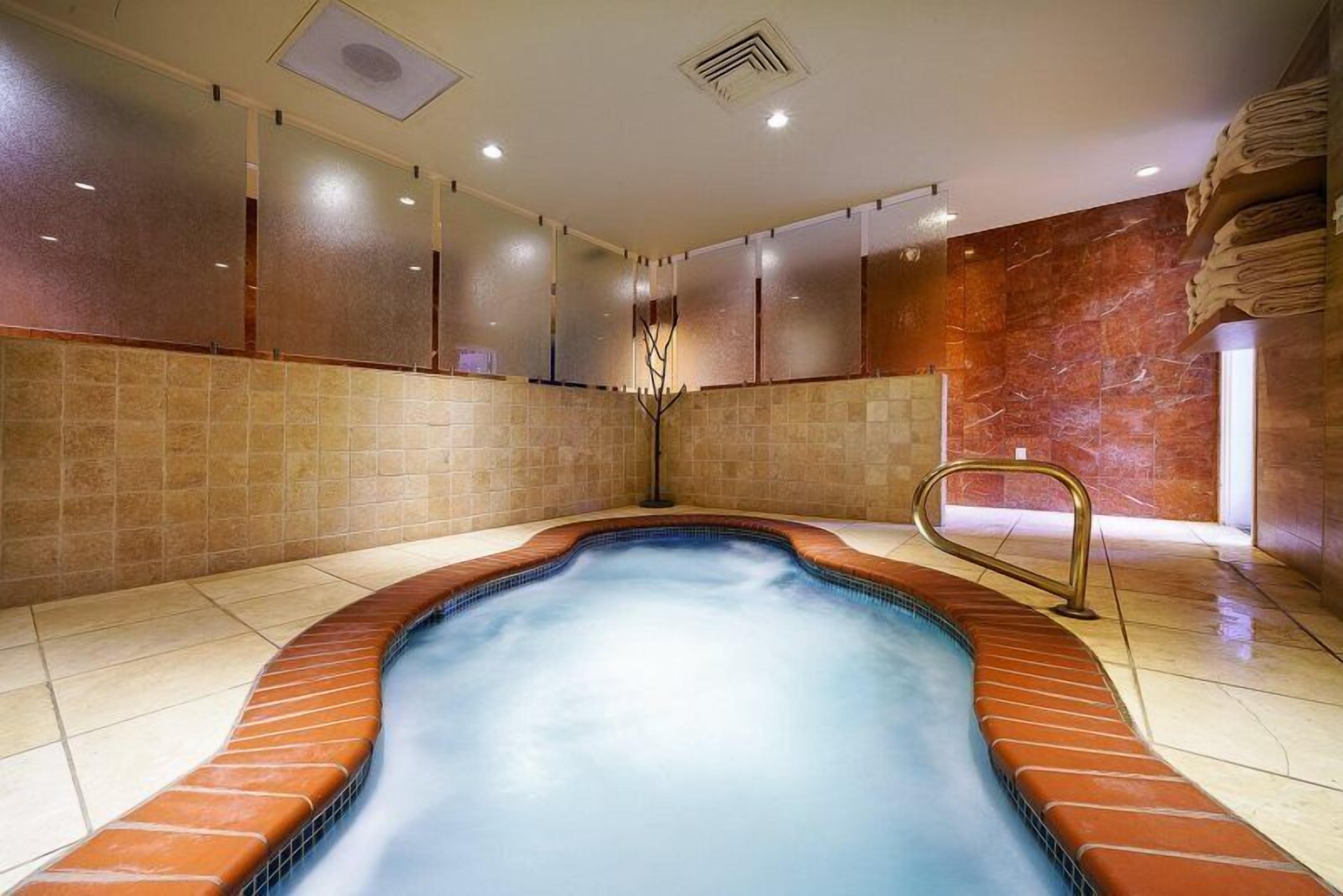 Un jacuzzi en una habitación con paredes de azulejos y una pared decorativa de mármol.