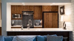 Eine moderne Küche mit Holzausstattung, einer Mikrowelle, einem Toaster und einer schwarz-weißen Spritzschutzwand.
