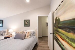Una camera da letto con un letto, un comodino e un quadro appeso al muro.
