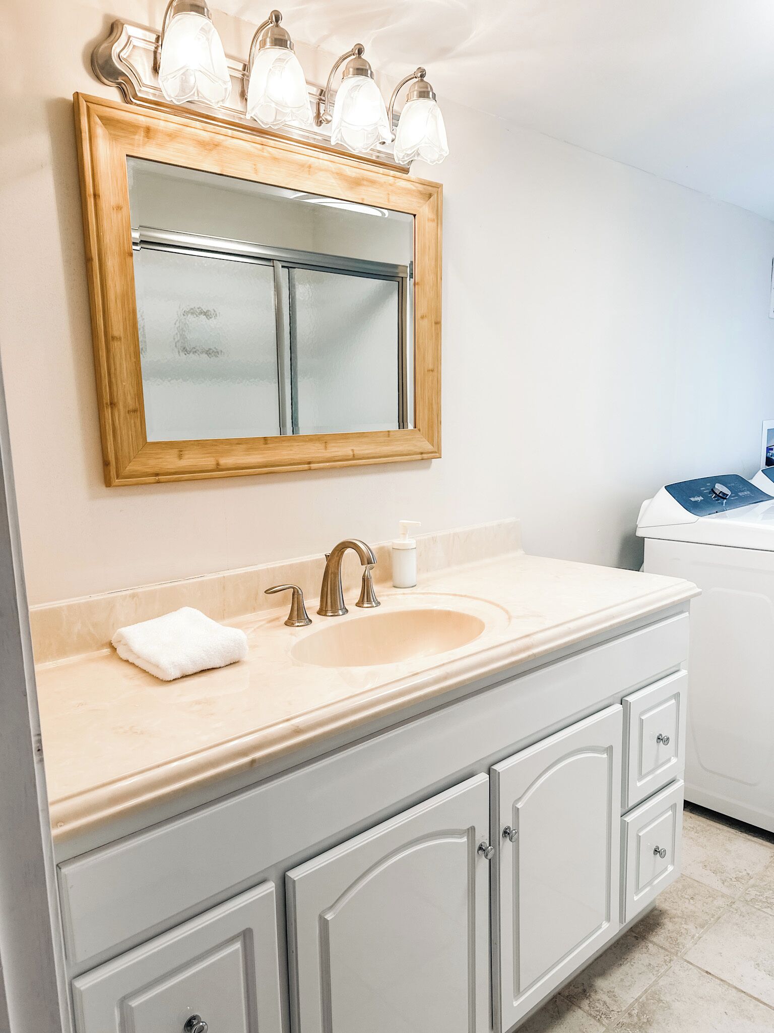 Une salle de bain avec un miroir encadré en bois, un lavabo avec un robinet et une serviette posée sur le comptoir.