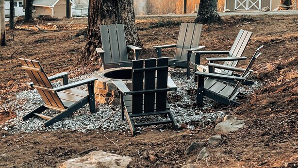 A rustic outdoor seating area with Adirondack chairs and a fire pit, surrounded by trees and a distant view of a barn and hills. - Soak In the Hot Tub @ County Top Cabin - Near I-77 & the Blue Ridge Parkway (Fancy Gap)