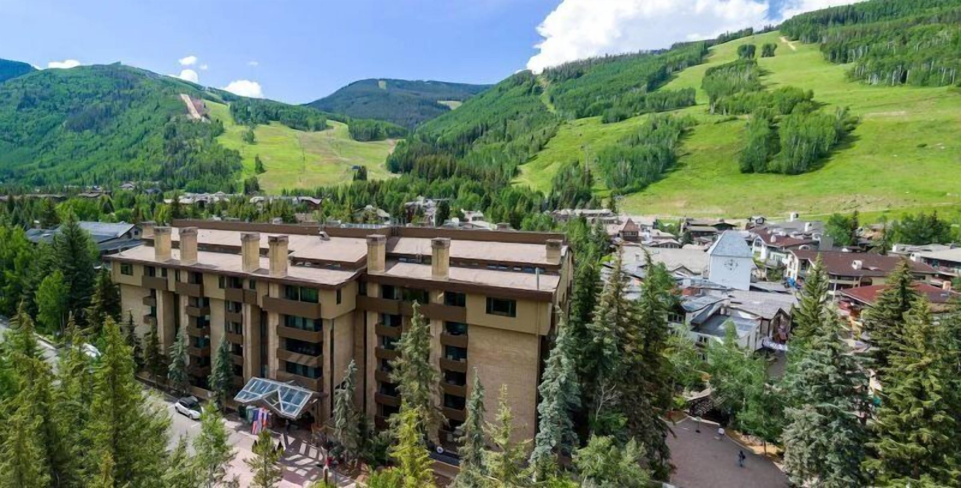 Un hôtel à plusieurs étages doté d’une cour intérieure, entouré d’une végétation luxuriante et de montagnes.