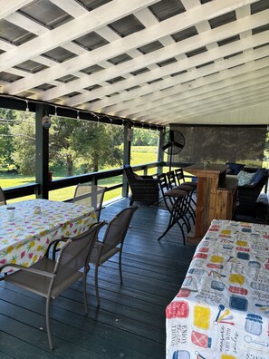 Une terrasse extérieure avec deux tables, des chaises et un ventilateur.