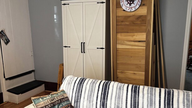 Une pièce chaleureuse avec un canapé à rayures, une porte en bois et une horloge au mur.