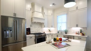 A modern kitchen with stainless steel appliances, white cabinetry, and a marble island.