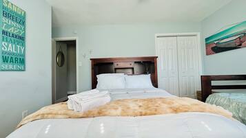 A neatly made bed with a fluffy blanket, a wooden headboard, and a wall with a list of words.