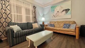 A living room with two sofas, a coffee table, a lamp, and a painting on the wall.