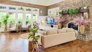 A spacious living room with a stone fireplace, a large TV, and a cozy seating area.