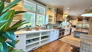 A spacious kitchen with white cabinetry, a large island, and a wooden dining table.