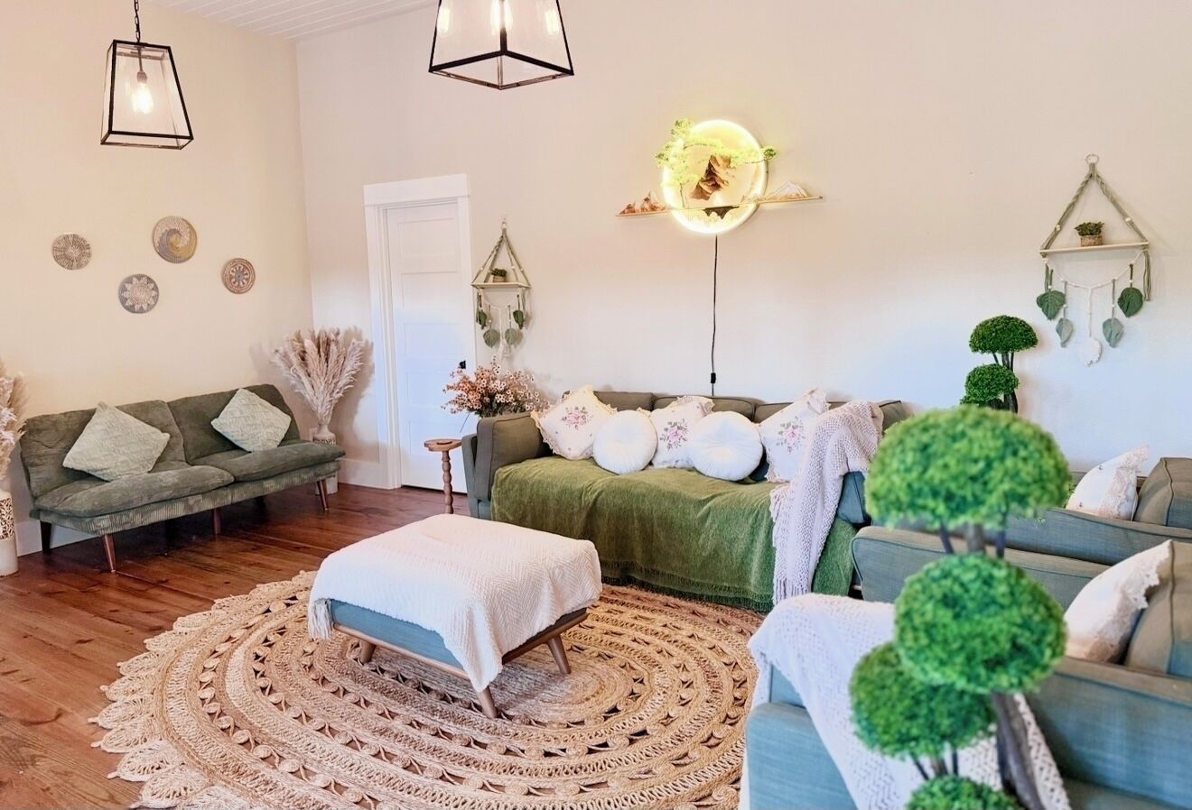 Una sala de estar acogedora con un sofá verde, un sofá azul, una mesa de centro redonda y una alfombra estampada.