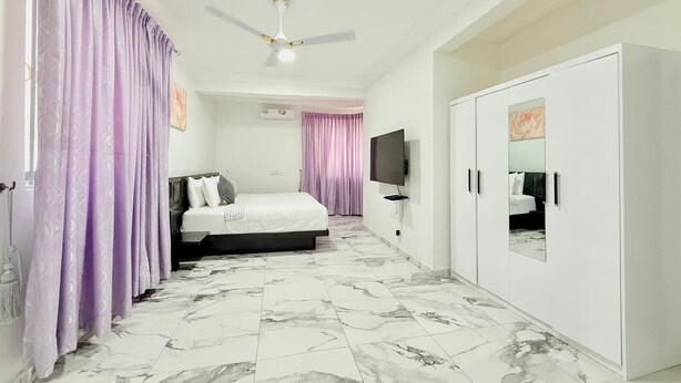 Une chambre à coucher avec un lit, une armoire, un ventilateur de plafond et un téléviseur.