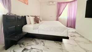 Une chambre à coucher avec un lit, une tête de lit, un sol en marbre et un tableau au mur.