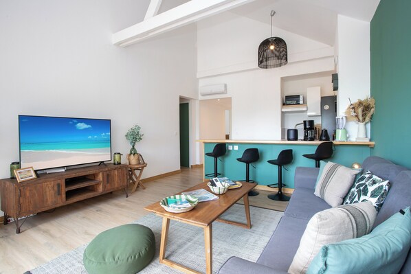 Un salon moderne avec un téléviseur, un meuble de rangement en bois et un canapé.