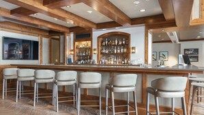 A bar area with wooden beams, a bar counter, and multiple stools. - Gorgeous 3 Bedroom Residence at The Ritz-carlton Club, Vail (Vail)