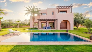 Een modern huis met een zwembad, een pergola en een verzorgd gazon.