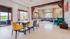 Een ruime woonkamer met een eettafel, stoelen en een zithoek.