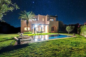A modern house with a swimming pool, a patio, and a starry night sky. - Konouz Palace (Marrakech)