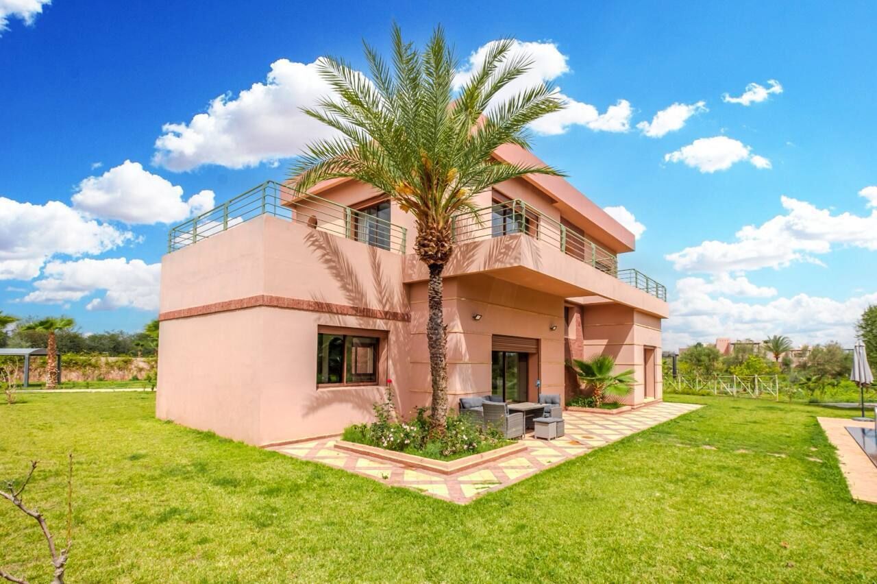 A two-story building with a flat roof, a balcony on the upper floor, and a small patio area with outdoor furniture.